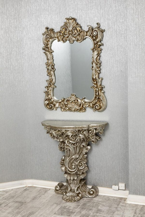 Decorative console table with ornate mirror against a gray wall.