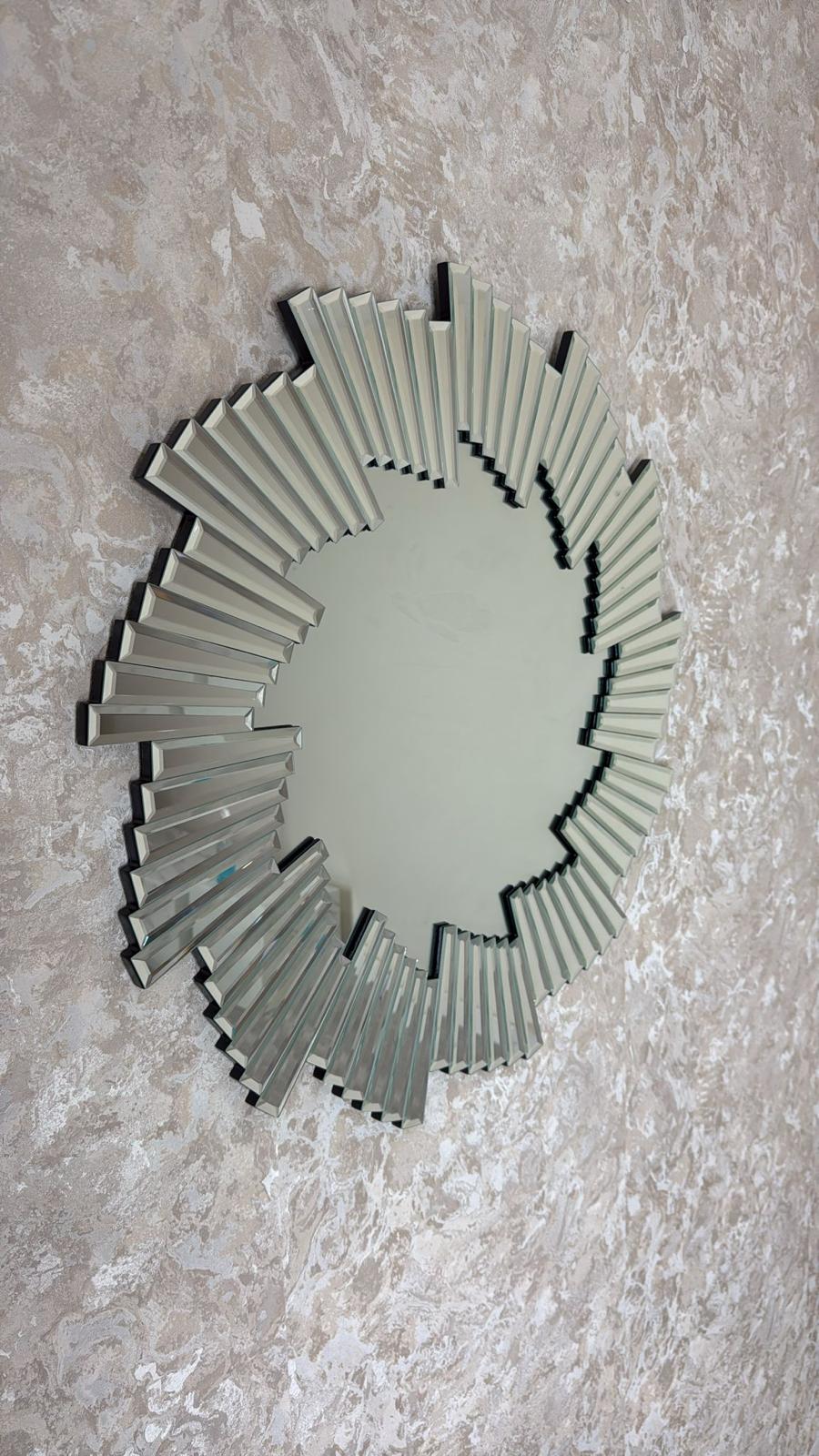 Decorative wall mirror with sunburst design on a textured wall