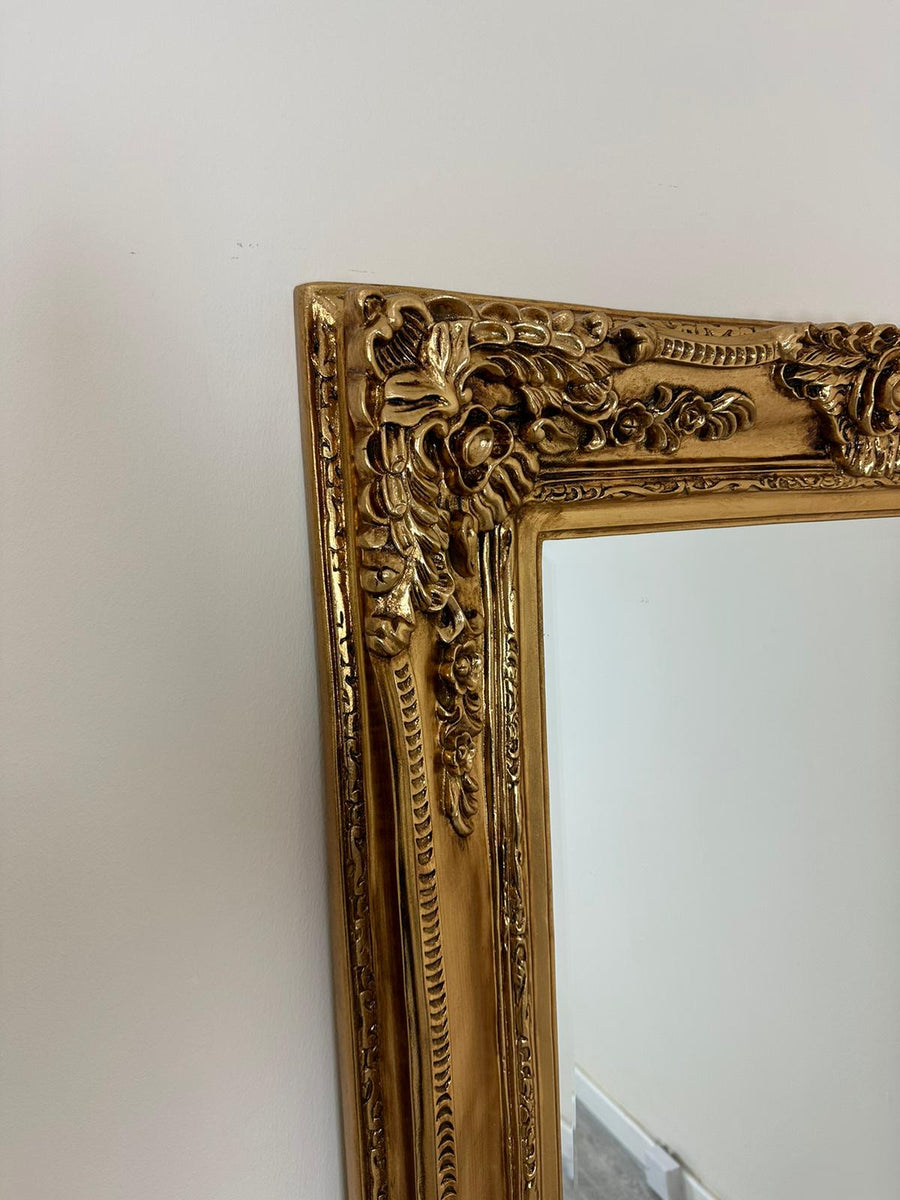 Gold ornate mirror on a white wall