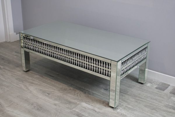 Coffee table with mirror-like surface and decorative frame on a wooden floor.