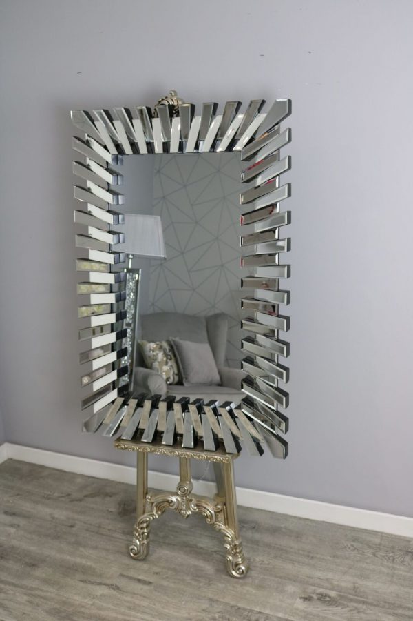 Decorative mirror with unique design on a stand against a gray wall.