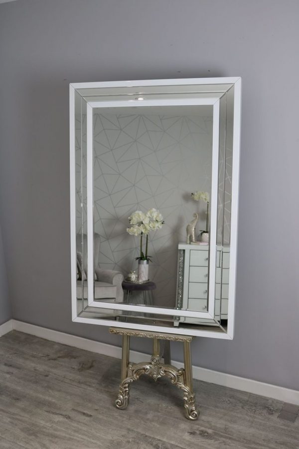 Decorative mirror with a white frame on a gray wall
