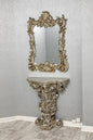 Decorative console table with ornate mirror against a gray wall.