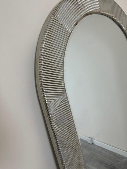 Round mirror with a decorative silver frame on a plain wall.