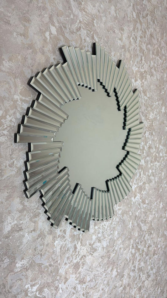 Decorative wall mirror with a sunburst design on a textured wall.