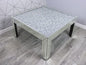 Coffee table with a glittery top in a room with geometric wall design.