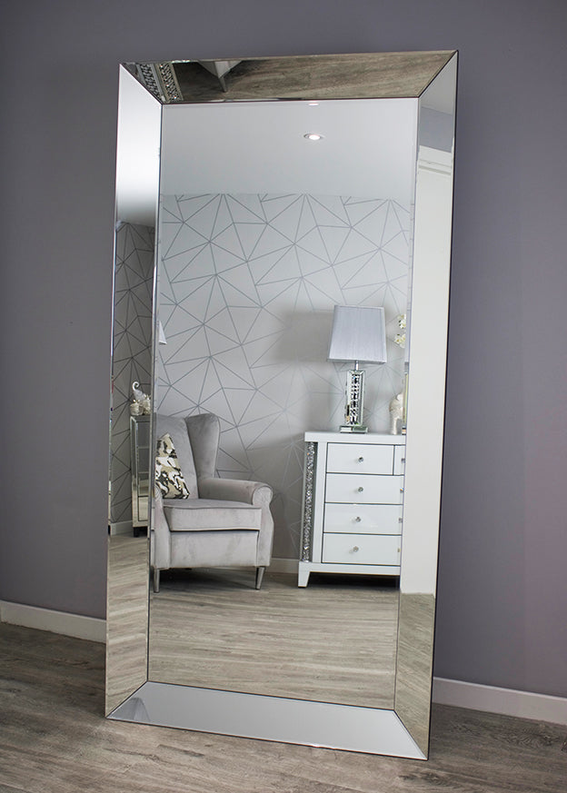 Large floor mirror reflecting a room with furniture and decor.