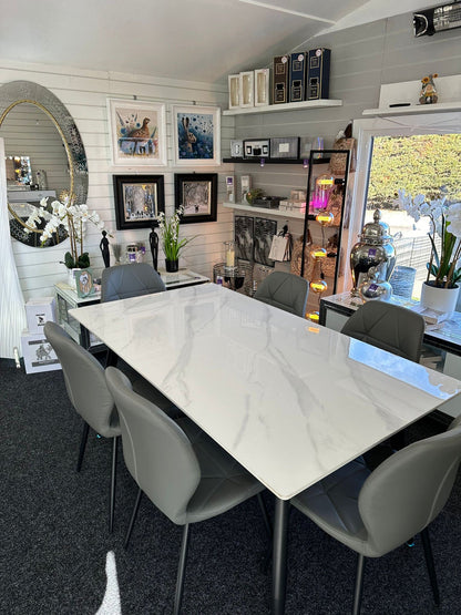 Dining room with a marble table and gray chairs in a home interior setting.