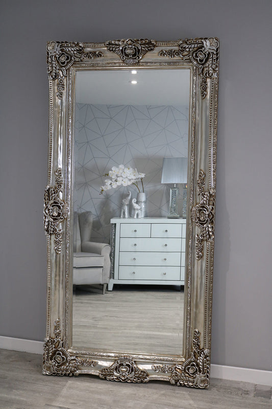 Decorative muted brownish-greyr mirror with intricate designs on a gray wall.