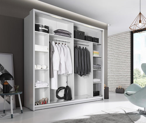Modern wardrobe with clothes and shelves in a room with a chair and lamp.