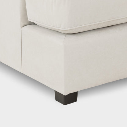 Close-up of a beige sofa with a black leg on a light gray background
