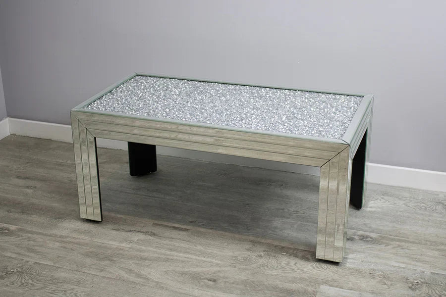 Coffee table with a reflective surface on a gray floor and wall.