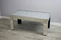 Coffee table with a reflective surface on a gray floor and wall.
